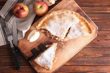 Pieces of tasty apple pie on wooden board