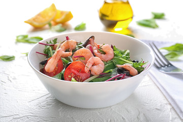 Bowl of delicious vegetable salad with seafood on white table