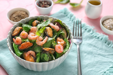 Bowl of delicious vegetable salad with seafood on table