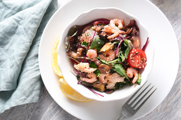 Bowl of delicious vegetable salad with seafood on table