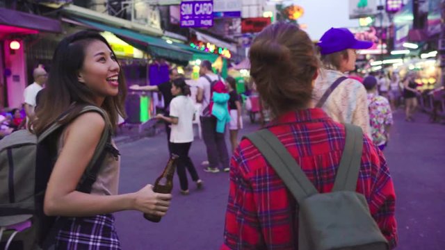 Traveler backpacker Asian women lesbian lgbt couple travel in Bangkok, Thailand. Female drinking alcohol or beer at The Khaosan Road the most famous street in Bangkok.