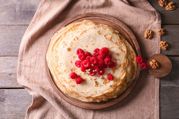 Delicious thin pancakes with berries on wooden board