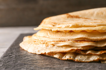 Delicious thin pancakes on slate plate, closeup