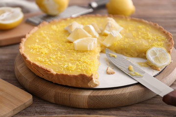 Tasty cut lemon pie on wooden table