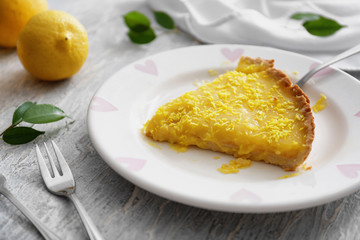 Plate with piece of tasty lemon pie on table, closeup