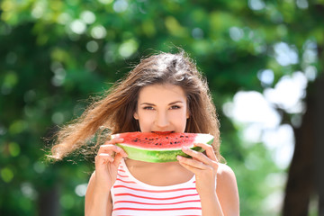 Beautiful young woman with slice of tasty watermelon outdoors