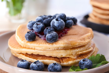Plate with tasty pancakes and blueberries on table, closeup
