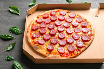Tasty Pepperoni pizza in cardboard box on table
