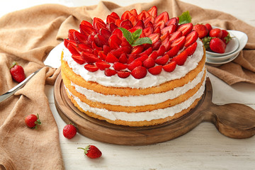 Delicious cake with strawberries on white wooden table