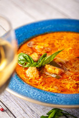 Italian European Cuisine. Spicy fish soup from seafood, salmon and trout, with vegetables in a blue...