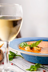 Italian European Cuisine. Spicy fish soup from seafood, salmon and trout, with vegetables in a blue plate. on the table in the restaurant is a glass of white wine. Copy space, selective focus