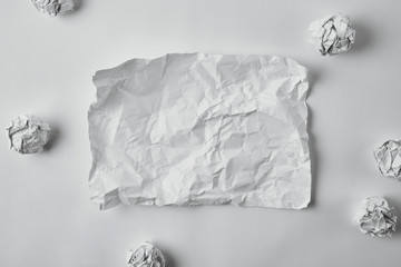 top view of blank damaged paper surrounded with crumpled papers on white surface