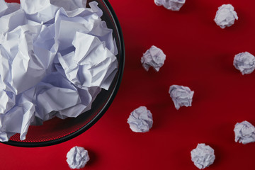 top view of office trash bin with crumpled papers on red tabletop