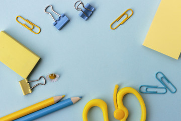 back to school or office styled concept, frame with blue and yellow school supplies on blue...