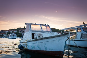Plakat Old boat in marina against sunset sky