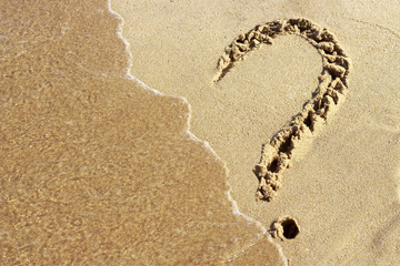 question mark drawn on a sandy beach and sea foam, close-up, top view