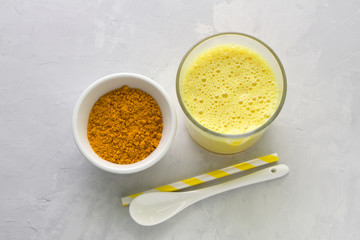 Golden milk with turmeric in a glass on a gray stone background. healthy natural energy drink. selective focus