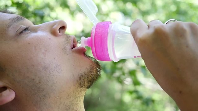 Man face closeup drinking water from sports bottle in slow motion