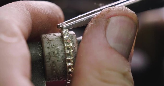 Close up of the hands of a goldsmith while he is working on a diamond ring.
