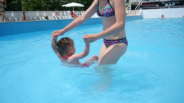 Mother with little kid child have fun teach swim in a swimming pool water on summer resort