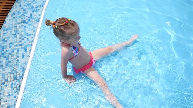 Little kid girl swim in a swimming pool clear water on summer resort