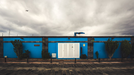 Cloudy and stormy landscape of old house on pier and flying plane.