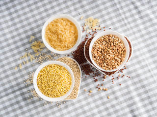 Gluten free grains quinoa, rice, buckwheat, amaranth, millet in bowls on kitchen table. Celiac diet