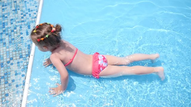 Little kid girl swim in a swimming pool clear water on summer resort