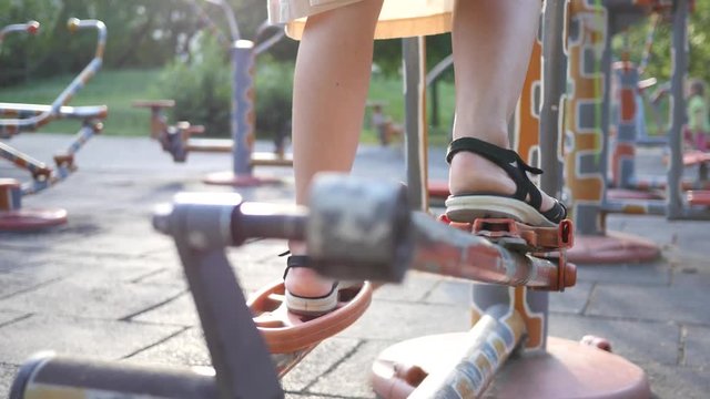 Fitness training ground in the park - woman legs twist the bicycle pedals