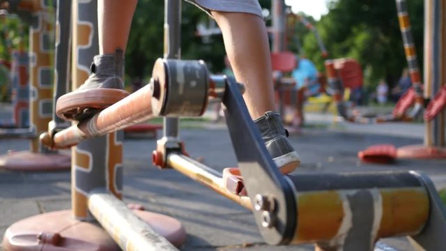 Fitness training ground in the park - kid boy legs twist the bicycle pedals