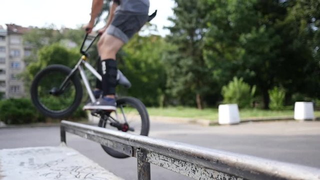 Riding a frystile tricks bike bicycle sliding over metal pipe in slow motion