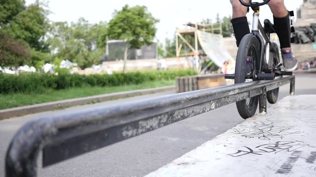 Riding a frystile tricks bike bicycle sliding over metal pipe in slow motion