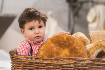 Portrait of a cute baby inside a basket with bread in the bakery