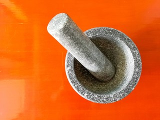 Dark granite stone mortar and pestle with red parquet background