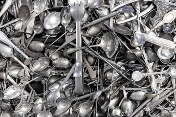 Silver spoons in a pile in a shop.