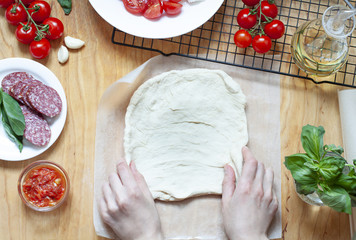 Pizza preparation on the wooden table. Food top view. Woman is making dough flat lay