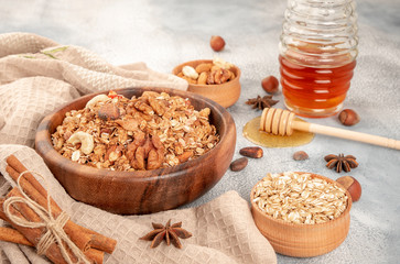 Homemade granola in wooden bowl with ingredients - oat, nuts, honey and spice cinnamon and anise