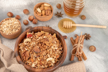 Homemade granola in wooden bowl with ingredients - oat, nuts, honey and spice cinnamon and anise