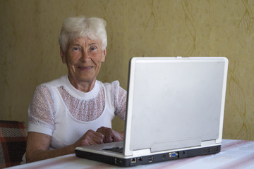 Portrait of smiling older woman working laptop computer indoors