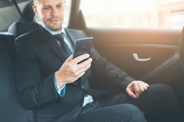 Executive businessman at the back of car using a mobile phone