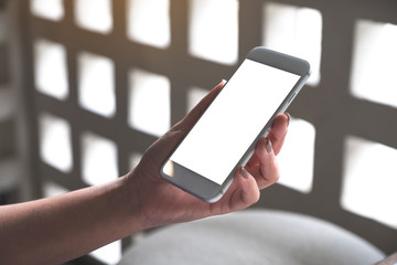 Mockup image of woman's hands holding white mobile phone with blank desktop screen in cafe
