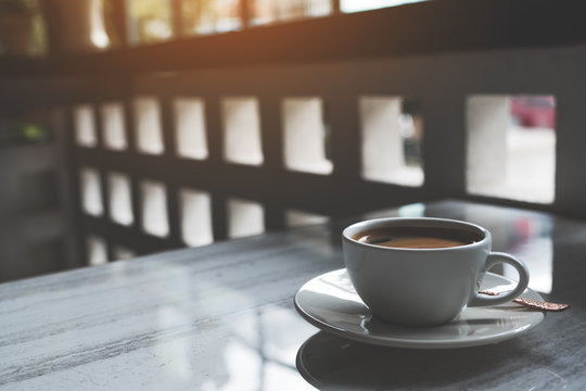 Closeup image of a white cup of hot coffee on table in cafe