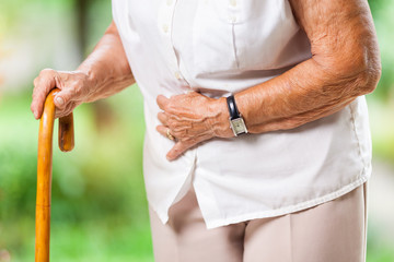 Elderly woman with a walking stick and stomach pain