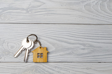 Naklejka premium House keys with house shaped keychain on wooden background