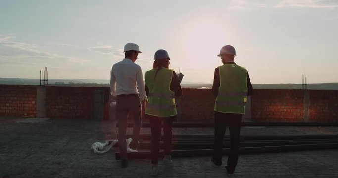Construction site on top of building with amazing sunset three engineers walking around. Slow Morions . 4k