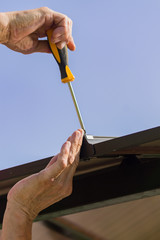 screwdriver in males hands. Worker with a hand tool assembling metal construction outdoors