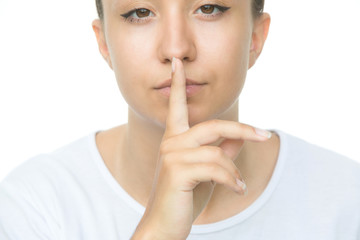 Secretive young woman placing finger on lips asking shh, quiet, silence isolated white background. Human face expressions, sign emotion feeling body language reaction