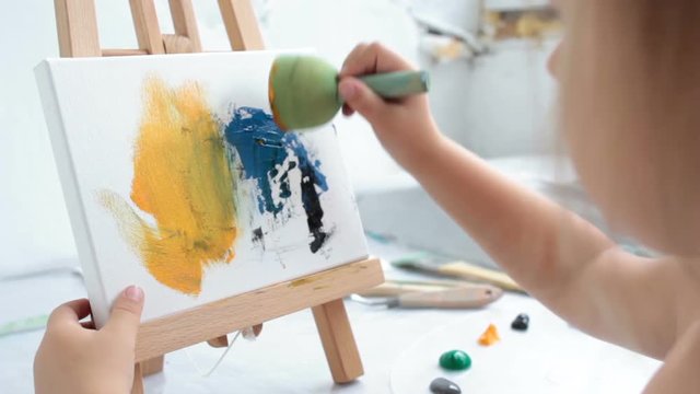 creative leisure. painting hobby. artful personality. talented child drawing abstract expressionist picture. mixing acrylic colors on canvas with sponge dauber.