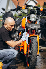 Fototapeta na wymiar Adult and experienced biker cleaning and washing his motorcycle