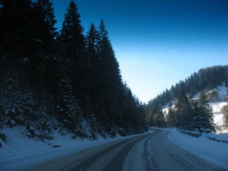 Fototapeta na wymiar Winter road in a ski resort with snow and coniferous trees